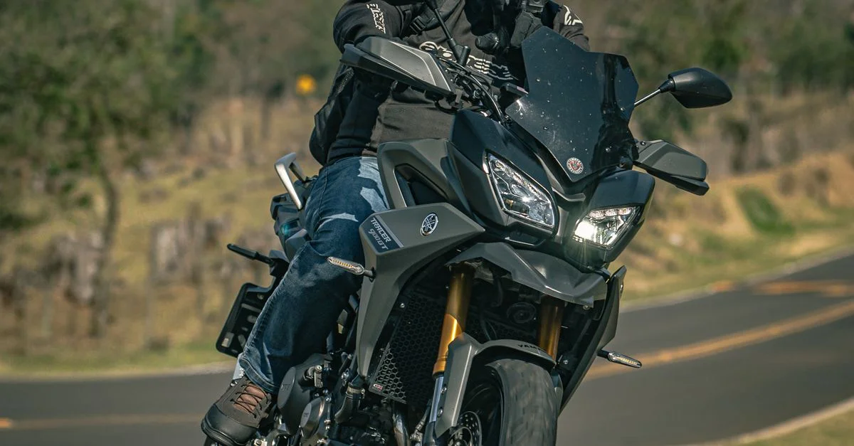 Un motard en équipement complet roule sur une Yamaha sur une route sinueuse, illustrant l'aventure et la vitesse.