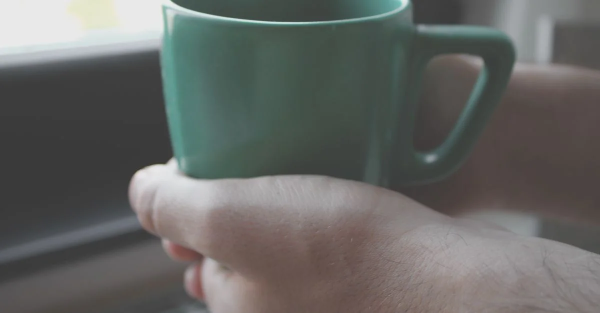 Profiter d'un thé aux herbes apaisant dans une tasse verte près de la fenêtre à Belgrade, Serbie.