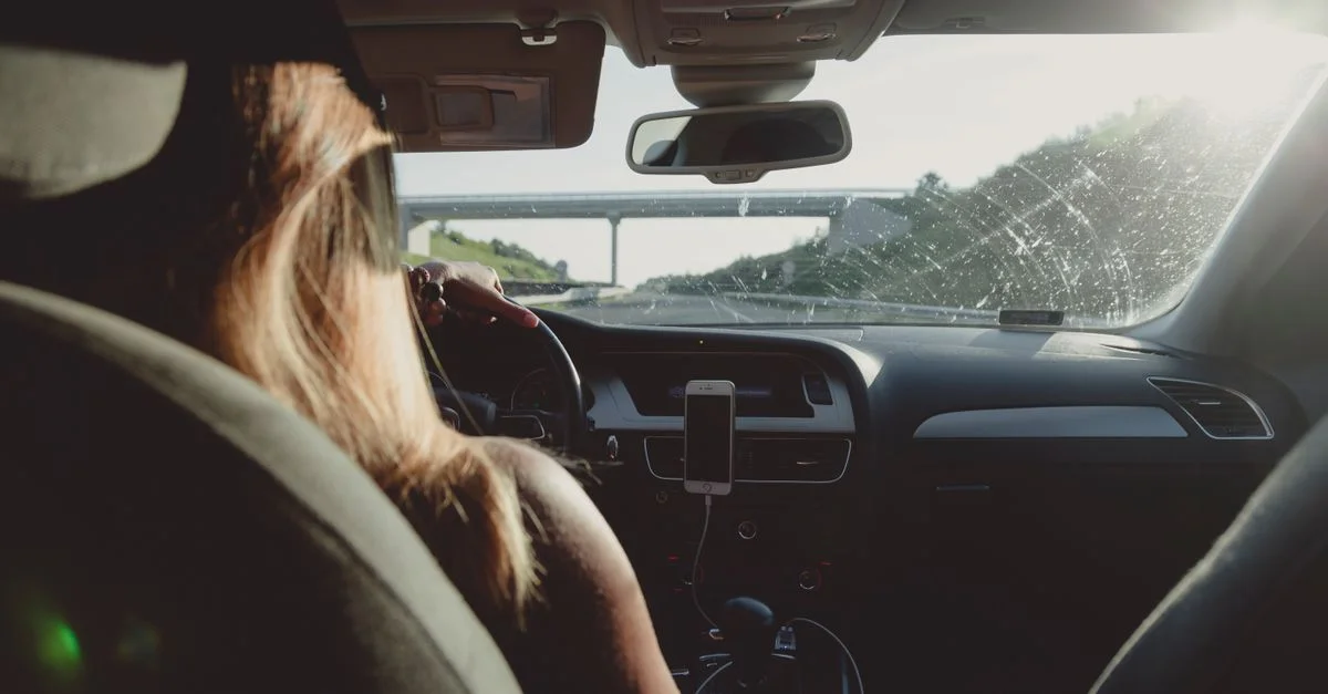 Femme conduisant sur une autoroute pendant la journée, capturant l'ambiance d'un road trip.