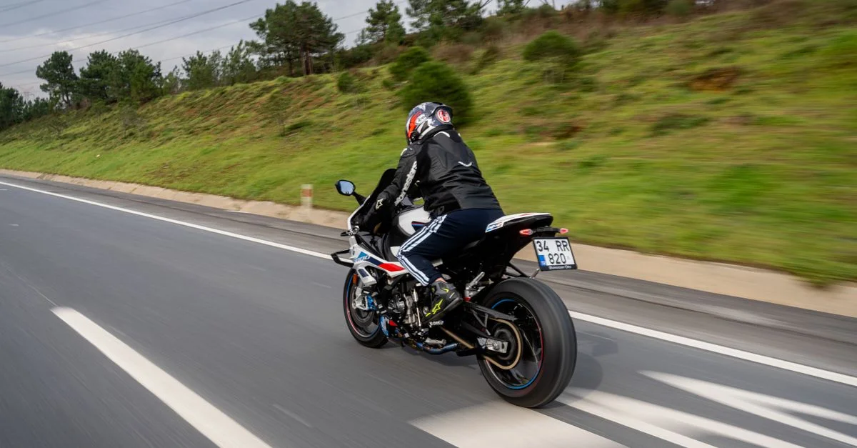 Personne montant une moto sur une autoroute, mettant en avant la vitesse et l'aventure.