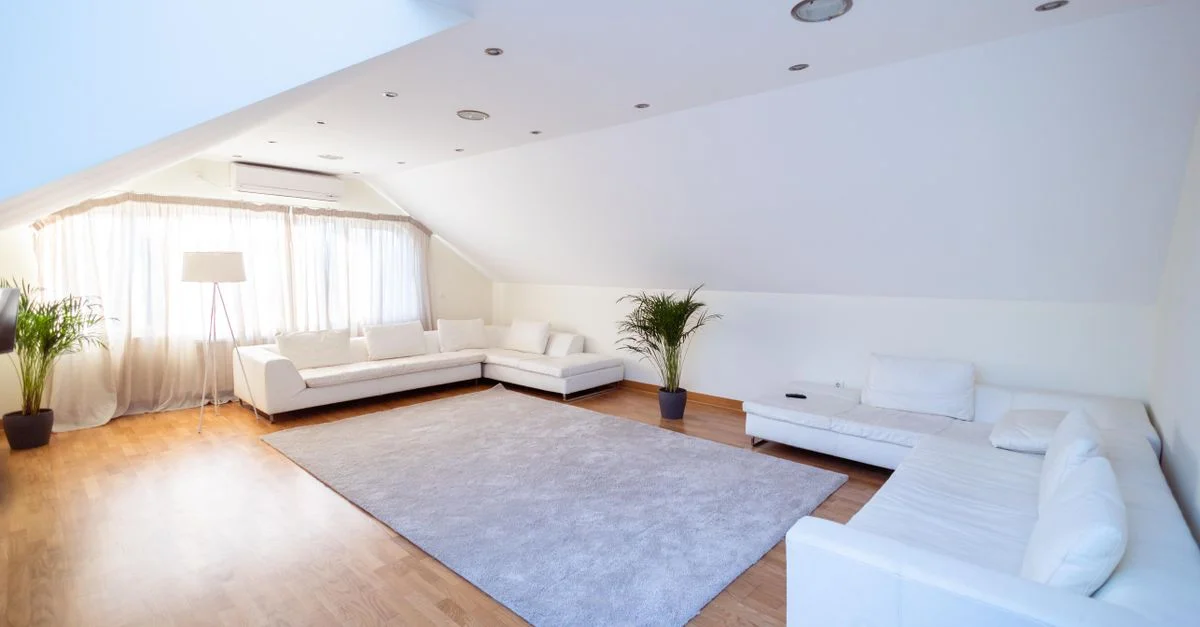 Salon moderne lumineux et aéré avec des canapés blancs, des plantes et un parquet en bois.